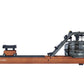 Apollo Pro rowing machine with wood base and black frame, featuring slide carriage seat and water resistance tank, side view 