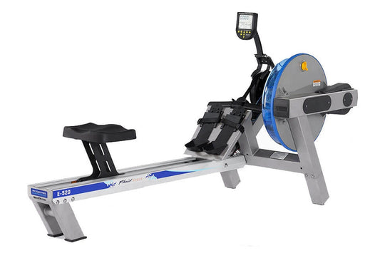 FluidRower E520 Evolution commercial rowing machine with gray frame, blue accents, digital monitor, and black footrest on whi