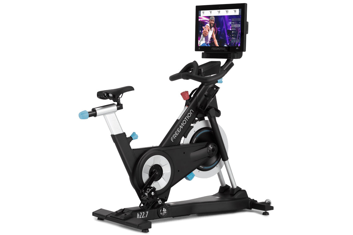 FreeMotion black and silver stationary exercise bike with blue accents, large flywheel, handlebar-mounted screen, and adjusta