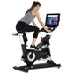 Woman on black and white stationary exercise bike with tablet display mounted, worn by model on white background
