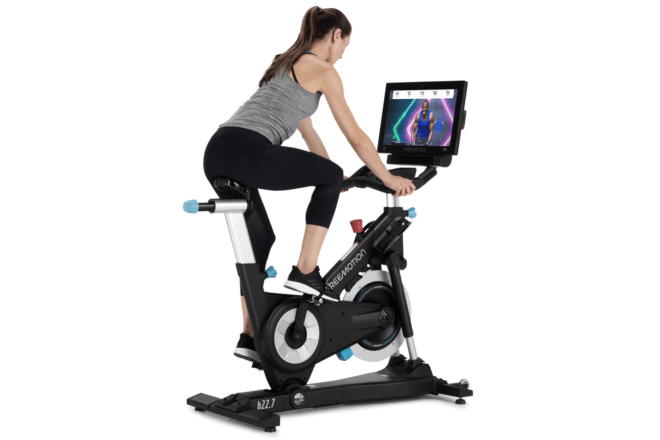 Woman on black and white stationary exercise bike with tablet display mounted, worn by model on white background