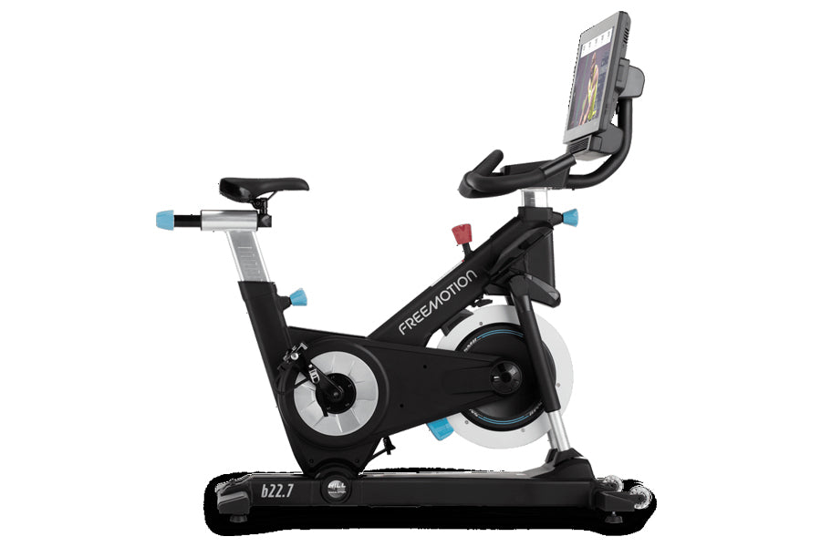 Freemotion CoachBike indoor exercise bike with black frame, blue accents, adjustable seat, handlebar, and mounted smartphone 