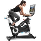 Woman exercising on black and white Freemotion stationary exercise bike with tablet screen mounted, wearing black tank top an