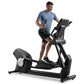 Man wearing blue t-shirt and black shorts using black Freemotion e10.9b elliptical machine with digital display on white back