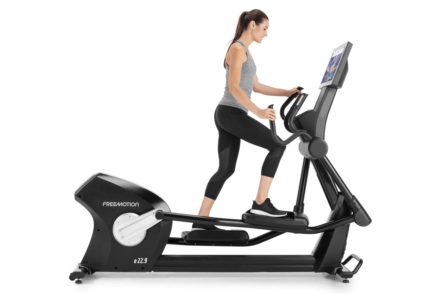 Woman using black Freemotion e22.9 elliptical with digital display, worn gray tank top and black capris