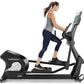 Woman using black Freemotion e22.9 elliptical with digital display, wearing gray tank top and navy capri leggings