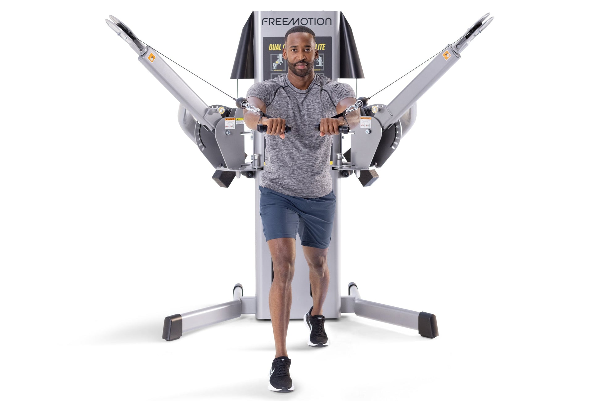 Man using Freemotion G424 Dual Cable Cross Lite machine with gray frame and black handles on white background