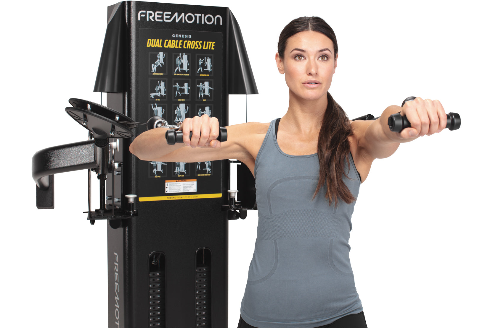 Woman using black Freemotion Genesis Dual Cable Cross Lite machine with exercise diagram display, holding handles in chest fl