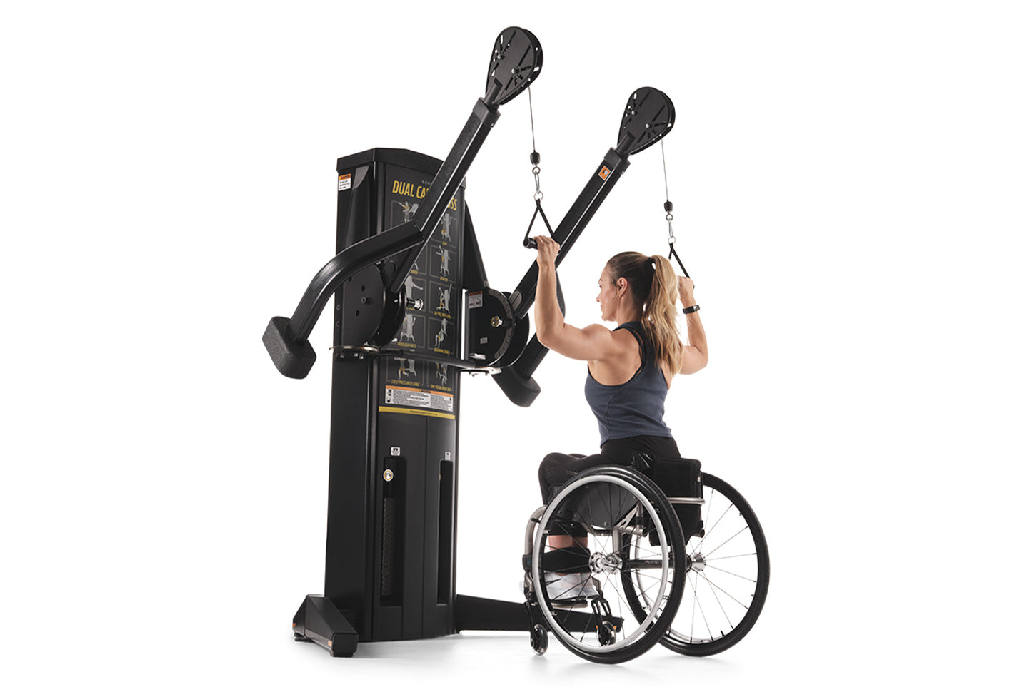 Black dual cable crossover machine with overhead pulleys, used by woman in wheelchair wearing navy tank top on white backgrou