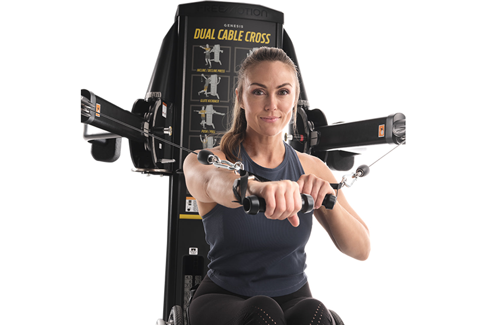 Woman using black Freemotion Genesis Dual Cable Cross machine with dual cable handles extended outward, on white background