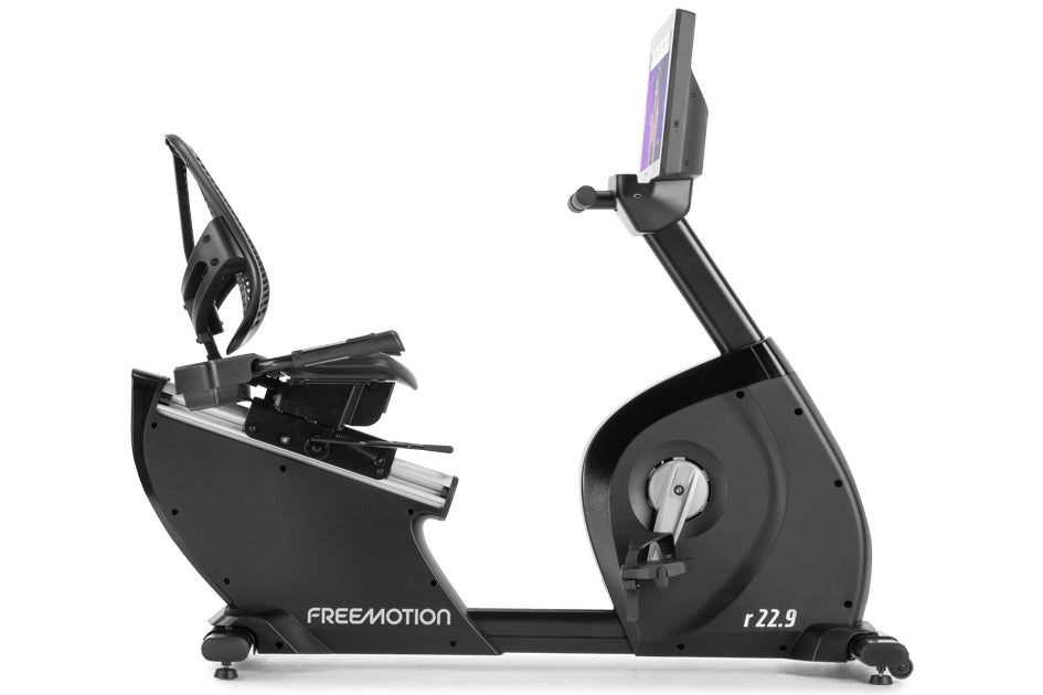 Freemotion r22.9 black recumbent exercise bike with tablet holder and foot pedals, side view on white background