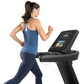 Woman running on black Freemotion treadmill with digital display, wearing blue tank top and navy leggings
