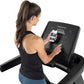 Woman wearing black racerback tank top using Freemotion t10.9b REFLEX treadmill with smartphone app displayed on screen