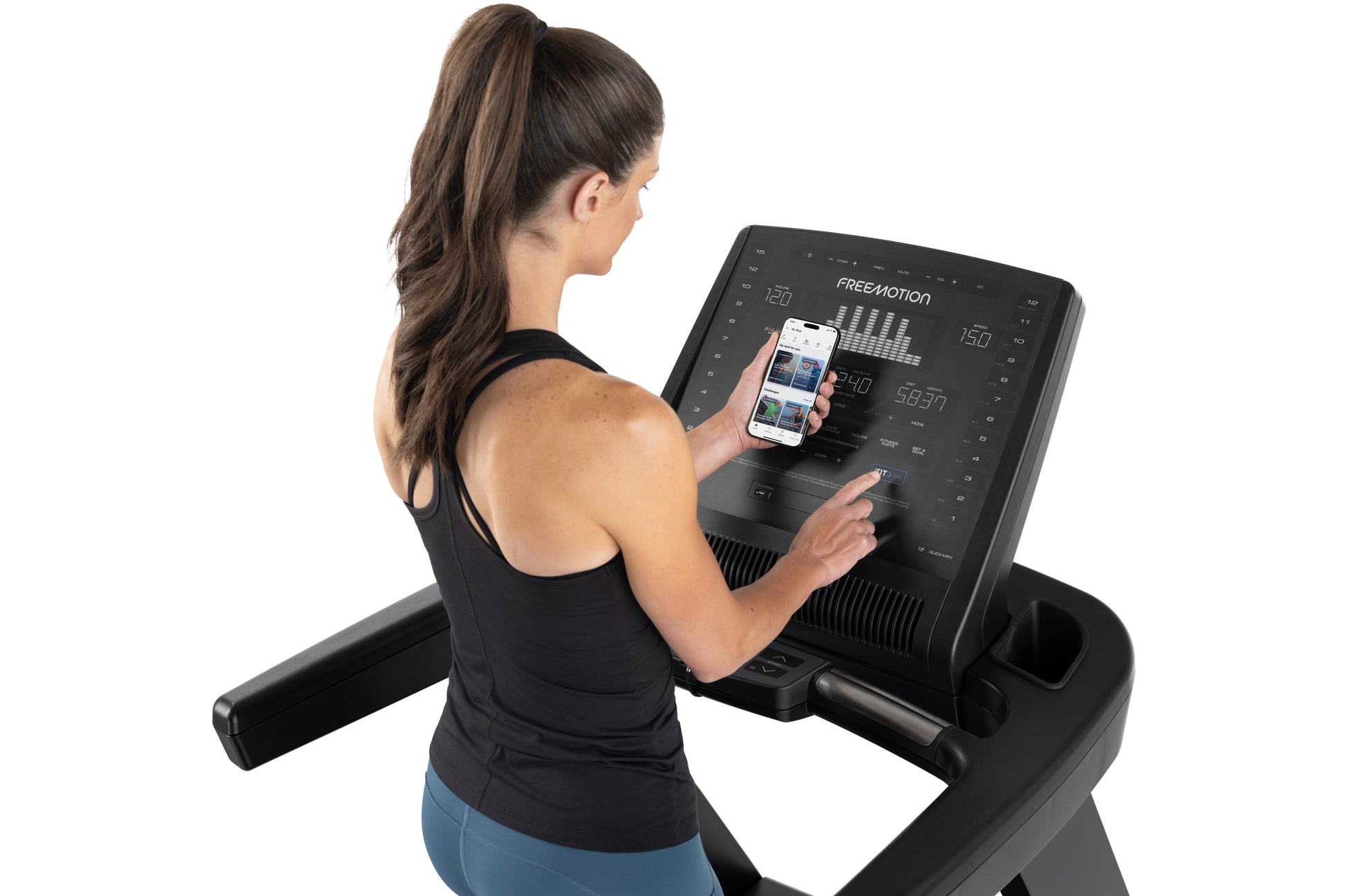 Woman wearing black racerback tank top using Freemotion t10.9b REFLEX treadmill with smartphone app displayed on screen
