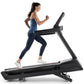 Woman running on black Freemotion REFLEX treadmill with incline, wearing blue tank top and navy leggings