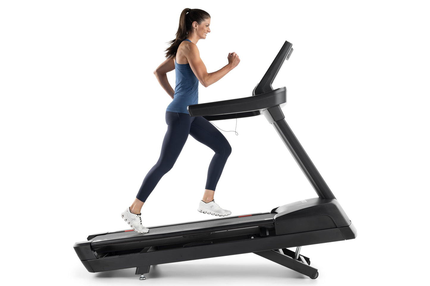 Woman running on black Freemotion REFLEX treadmill with incline, wearing blue tank top and navy leggings