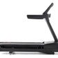 Black motorized treadmill with digital console, handrails, and red accent stripe on running deck, side view on white backgrou