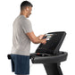 Man wearing gray t-shirt and navy shorts using black Freemotion treadmill with digital display on white background