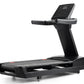 Black Freemotion t10.9b REFLEX treadmill with digital display console, handrails, and cushioned running deck on white backgro