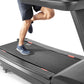 Person running on gray Freemotion t22.9 REFLEX treadmill with dark running shorts and navy sneakers