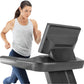 Woman wearing light gray sleeveless tank top and navy leggings running on black Freemotion T22.9 REFLEX treadmill with digita