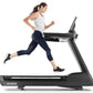 Woman running on black t22.9 REFLEX treadmill wearing gray tank top and navy capri leggings