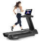 Woman running on black Freemotion t22.9 REFLEX treadmill with touchscreen display showing workout content, white tank top and