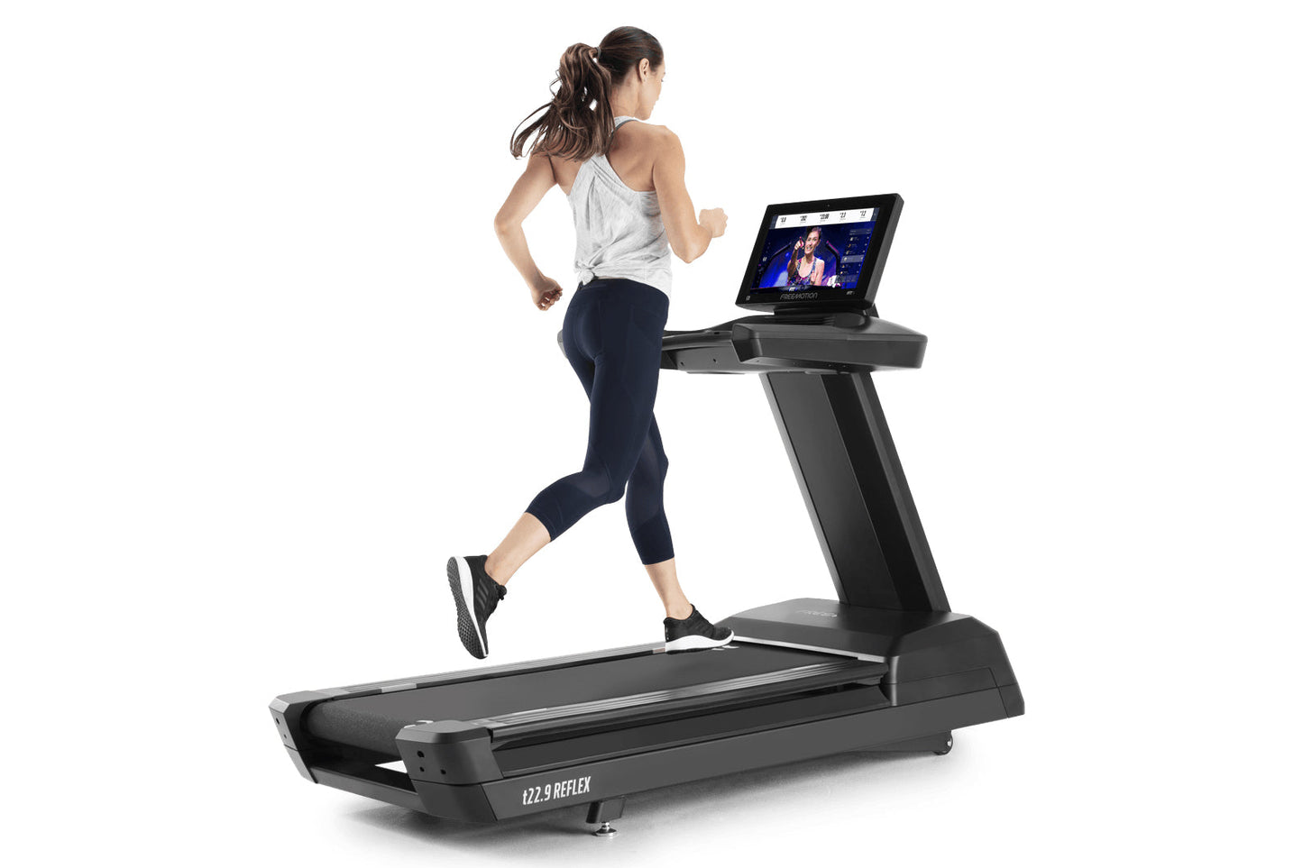 Woman running on black Freemotion t22.9 REFLEX treadmill with touchscreen display showing workout content, white tank top and