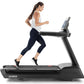 Woman running on black Freemotion t22.9 REFLEX treadmill with digital display, wearing white tank top and navy capri leggings