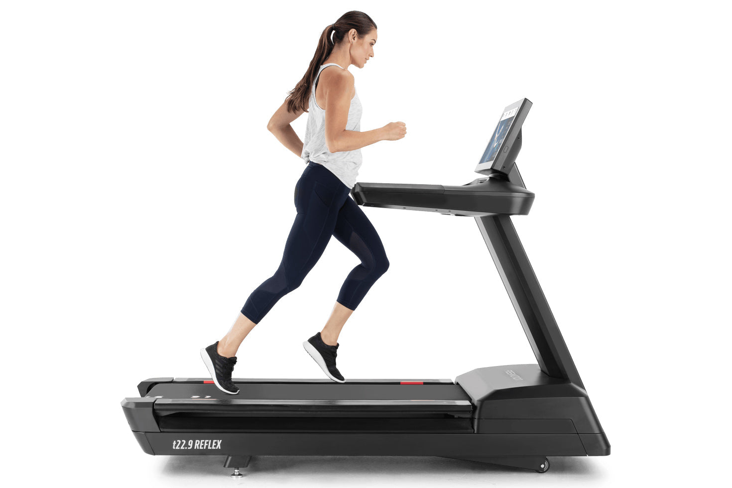 Woman running on black Freemotion t22.9 REFLEX treadmill with digital display, wearing white tank top and navy capri leggings