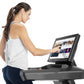 Woman in white tank top and navy pants using Freemotion t22.9 REFLEX treadmill with touchscreen display