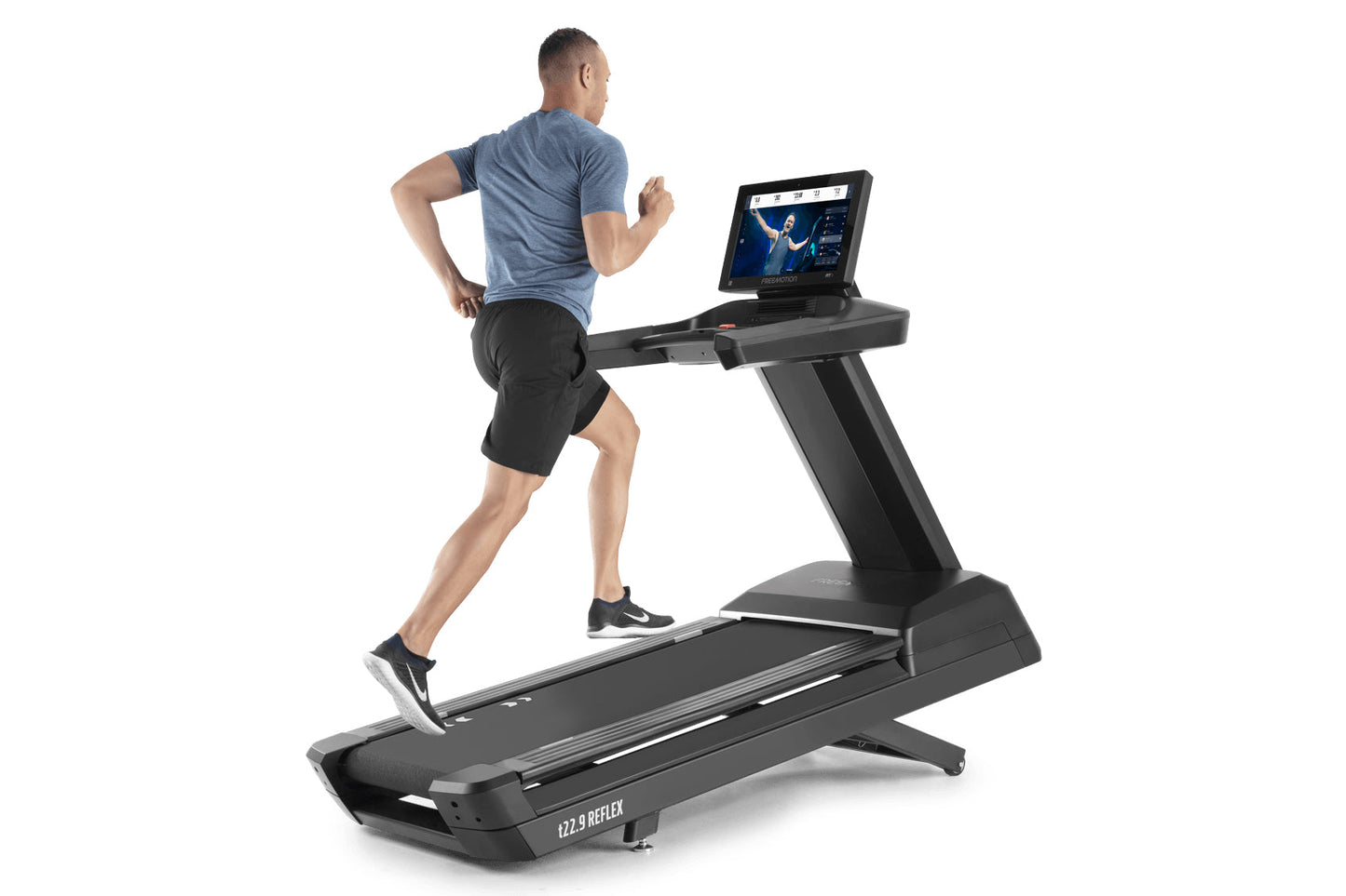 Man running on black Freemotion t22.9 REFLEX treadmill with touchscreen display, wearing blue t-shirt and black shorts