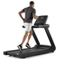 Man running on black Freemotion t8.9b treadmill with digital display, wearing gray t-shirt and white shorts