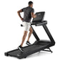 Man running on black Freemotion t8.9b treadmill with digital display console, wearing dark t-shirt and white shorts