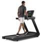 Man jogging on black Freemotion t8.9b treadmill with digital display, wearing gray shirt and white shorts