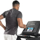 Man wearing charcoal t-shirt and white shorts using Freemotion t8.9b treadmill with digital display showing workout metrics
