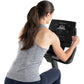 Woman wearing gray sleeveless top and navy pants using Freemotion u10.9b upright exercise bike with black digital display con