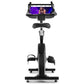Black upright exercise bike with tablet holder displaying fitness class, padded seat, dual handlebars, and foot pedals on whi