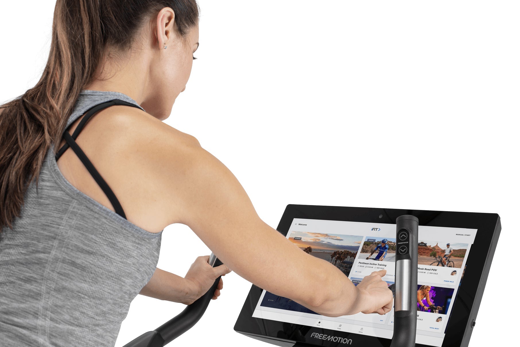 Woman wearing gray sleeveless tank top with black straps using upright exercise bike with digital screen displaying fitness c