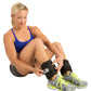 Woman wearing blue sports bra and gray shorts adjusting black GoFit ankle weights with white label, worn with gray and neon y