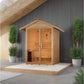 Golden Designs Arlberg cedar wood sauna with pitched roof, double glass doors, and bench seating in outdoor setting with pott
