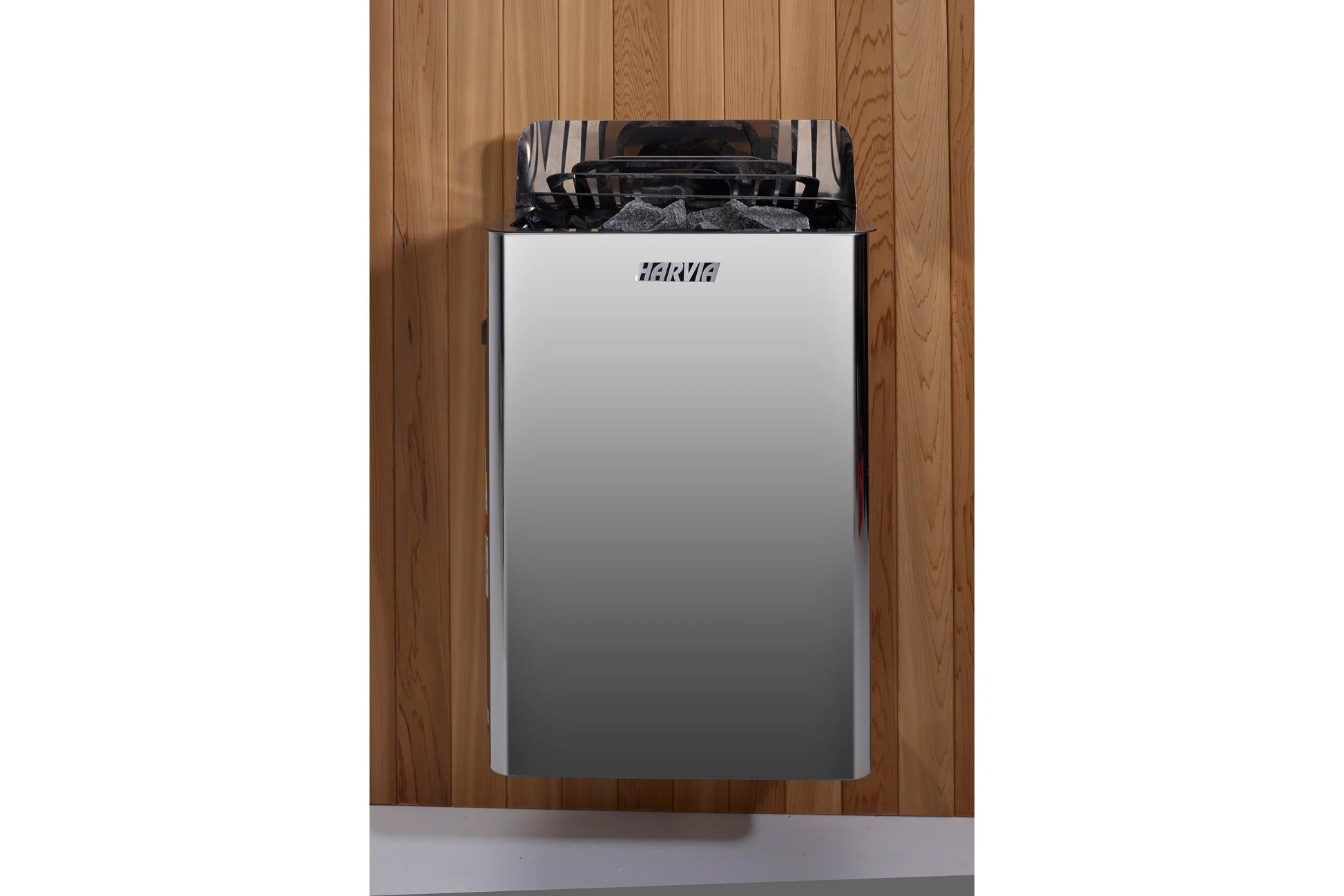 Harvia stainless steel and black sauna heater with rocks visible inside, mounted on wooden wall background
