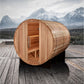 Cylindrical cedar barrel sauna with open door revealing wooden interior, positioned on wooden deck with snow-capped mountains