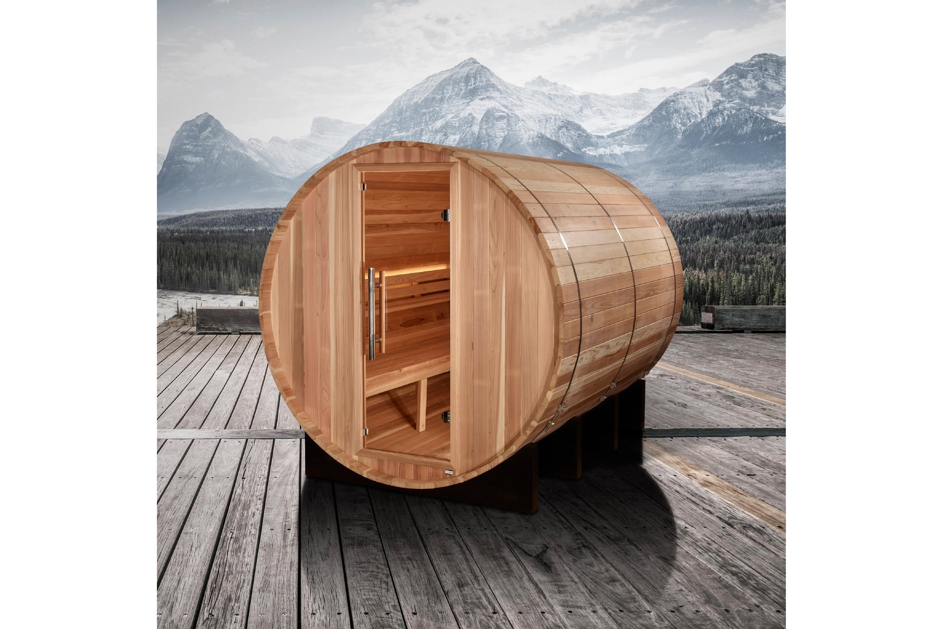 Cylindrical cedar barrel sauna with open door revealing wooden interior, positioned on wooden deck with snow-capped mountains