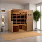 Four-person wooden sauna with glass door and infrared heater panels visible inside, positioned in modern bedroom setting on t