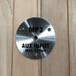 Brushed metal circular panel with MP3 and AUX INPUT MAX 175mV text, mounted on light wood background