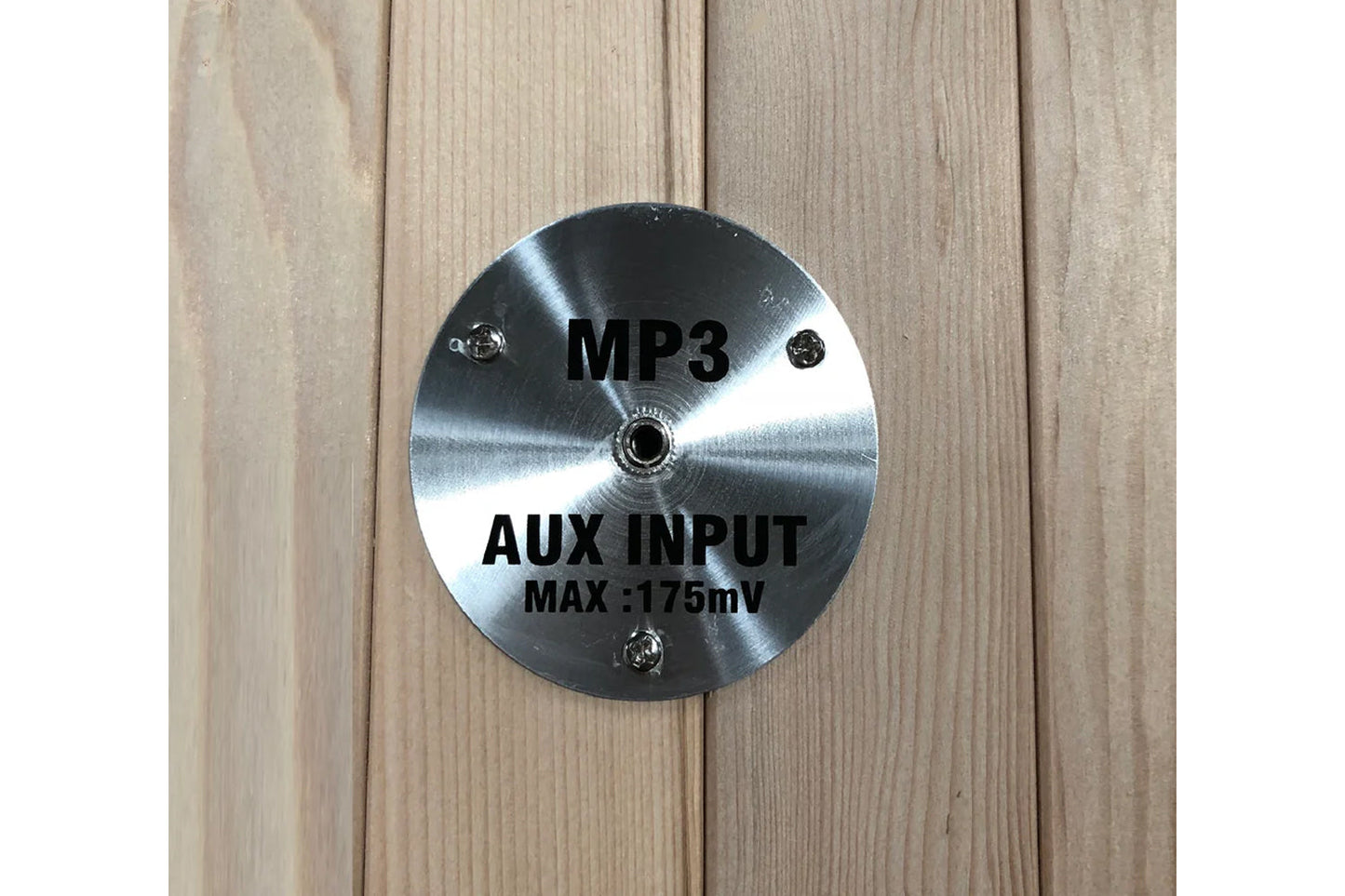 Brushed metal circular panel with MP3 and AUX INPUT MAX 175mV text, mounted on light wood background