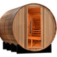 Wooden barrel sauna with natural cedar exterior, open glass door revealing orange-tinted interior with wooden benches and met