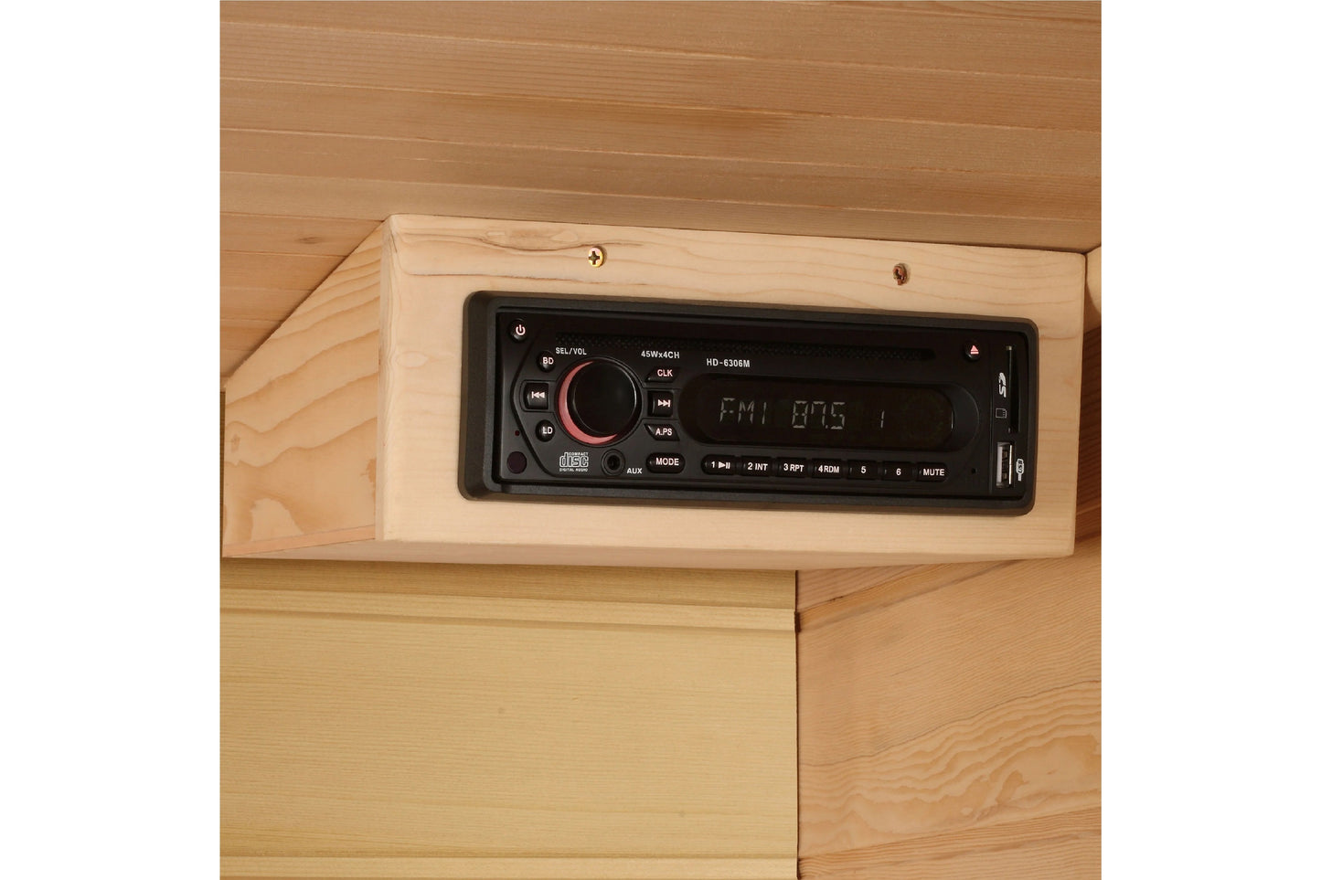 Black digital car stereo with red volume knob mounted in light wood frame inside sauna