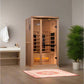 Cedar wood infrared sauna with glass doors and interior heaters, displayed in a bathroom setting with potted plant and vanity